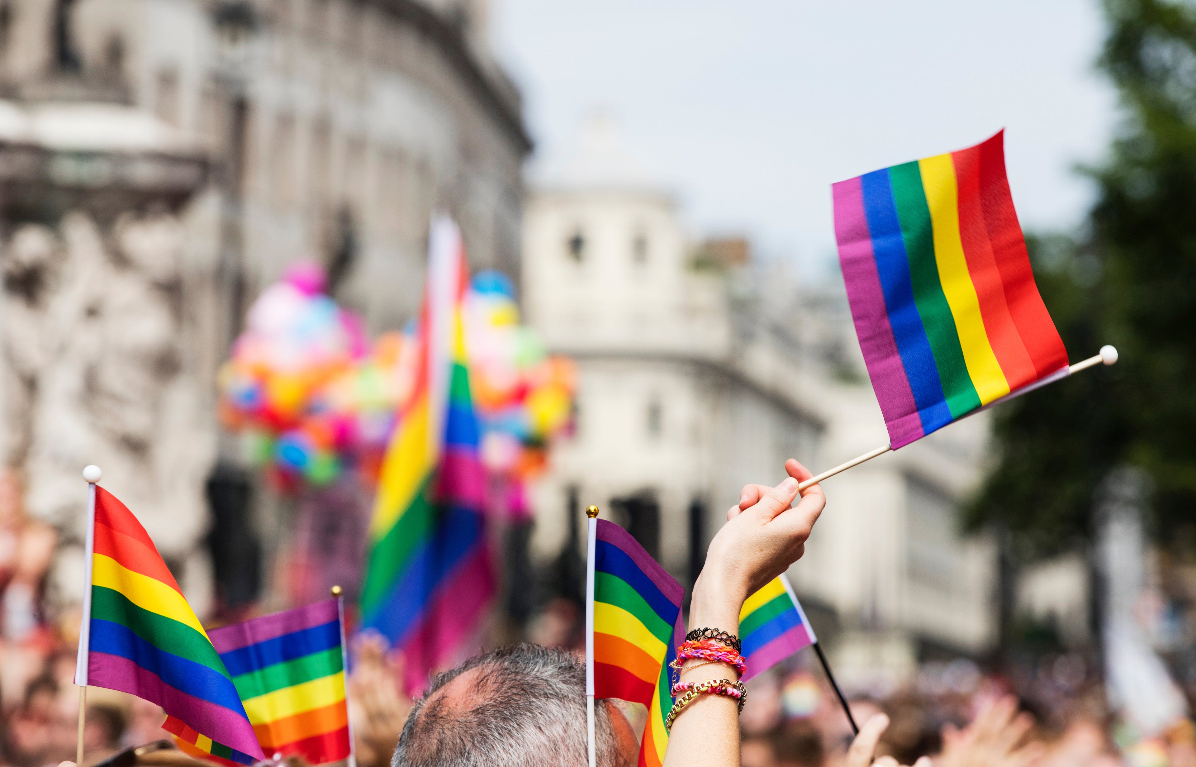 Images of pride flags being held over the heads of parade goers.